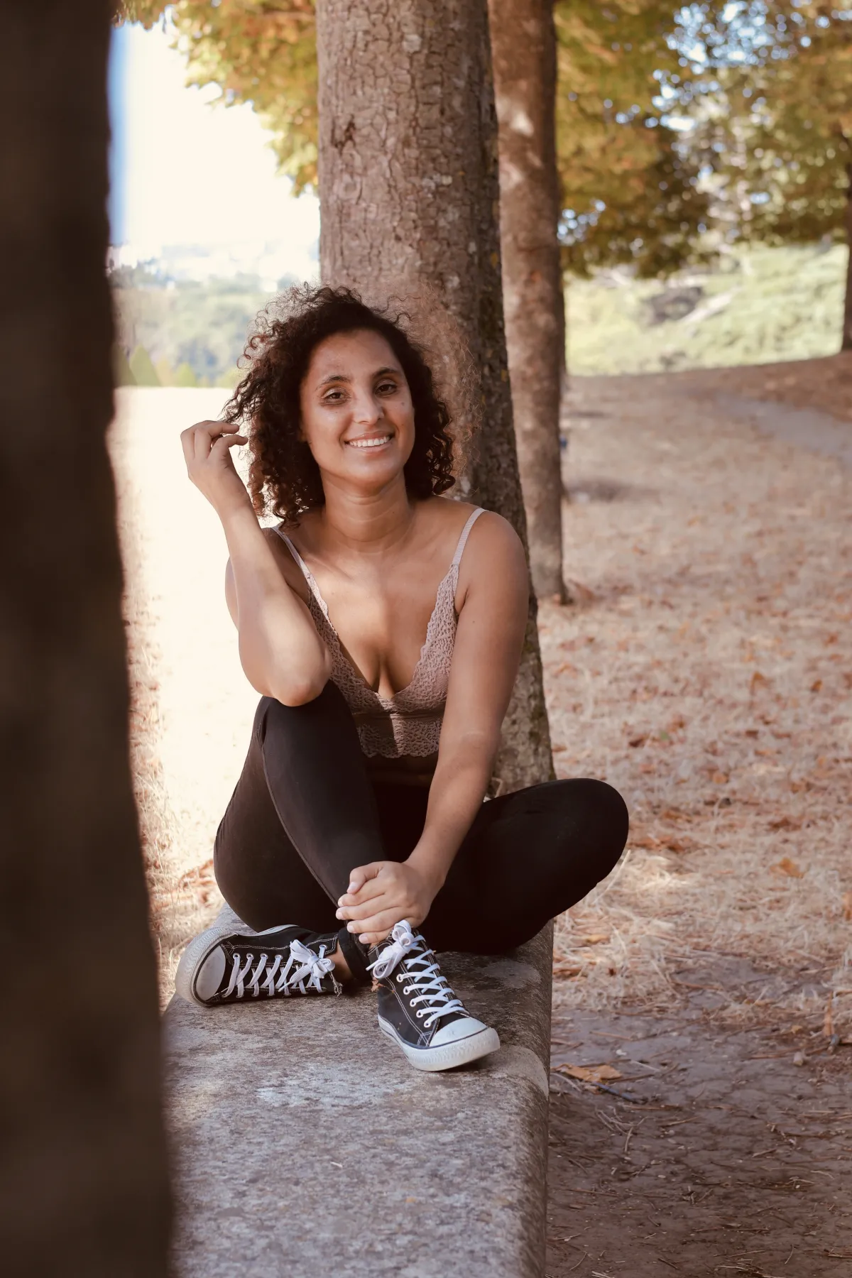 Jeune femme souriante assise sous les arbres en automne