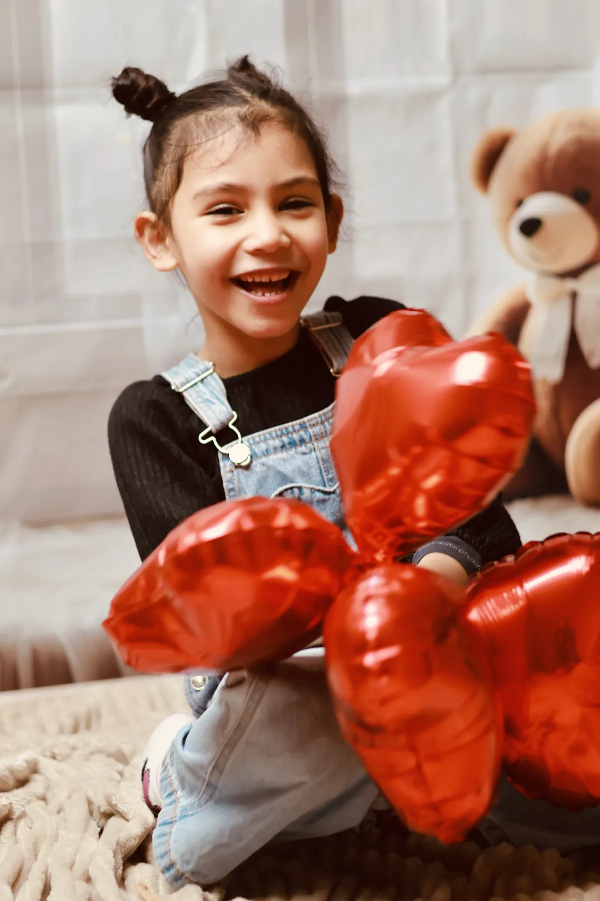 Une fillette rieuse tient des ballons en forme de cœur