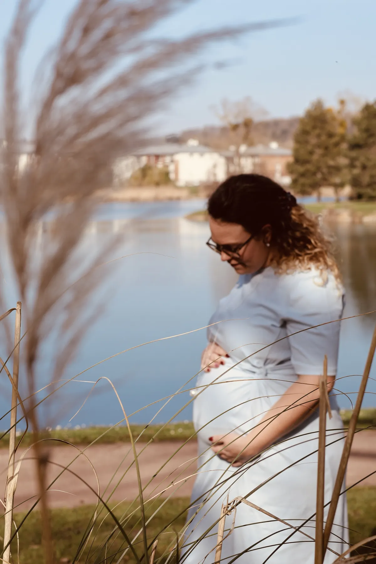 Femme enceinte au bord d'un lac entre les herbes hautes