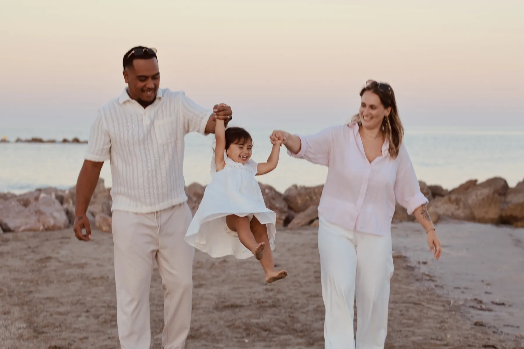 Des parents font sauter leur fillette sur la plage au crépuscule