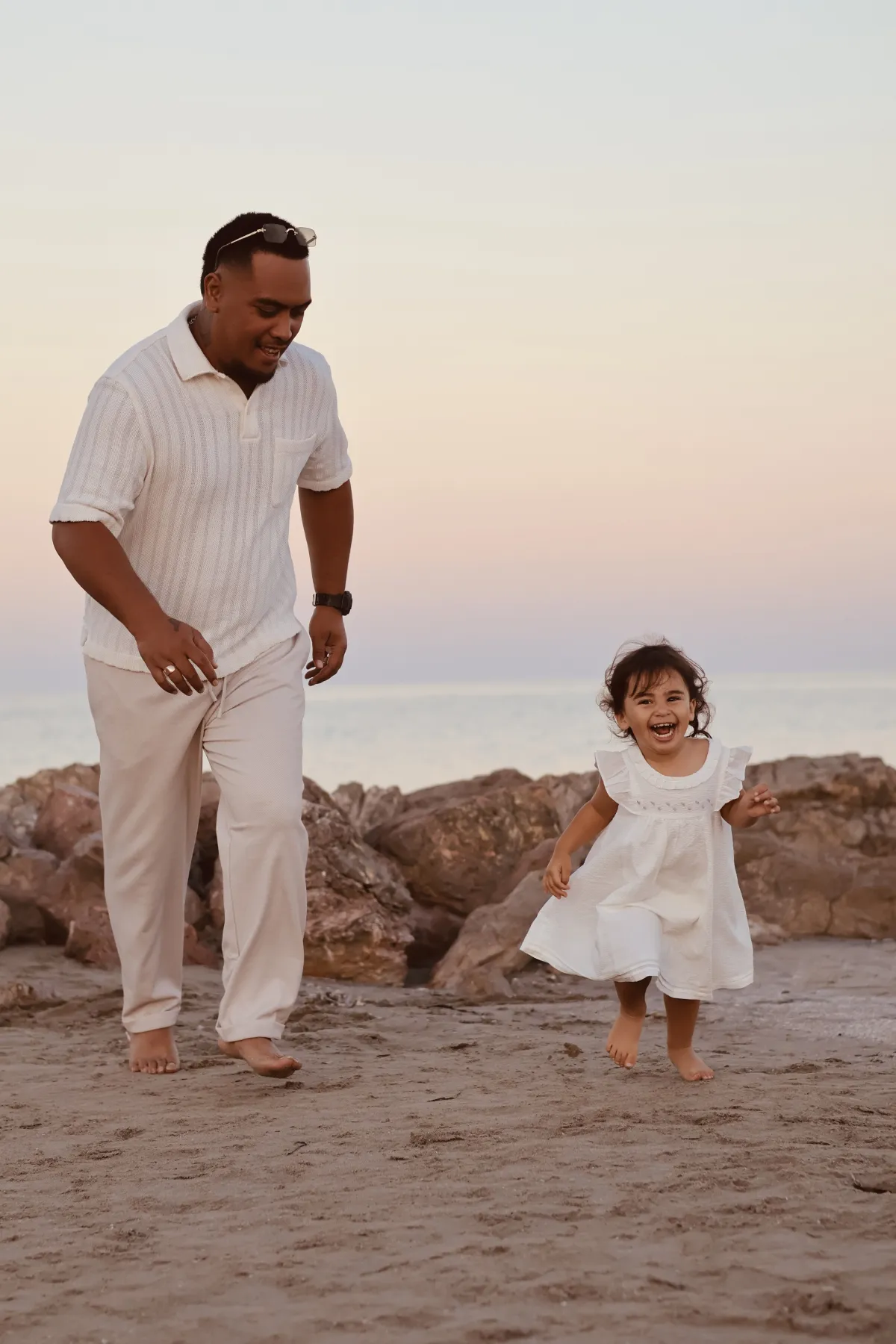 Un papa et sa fillette courent joyeusement sur la plage