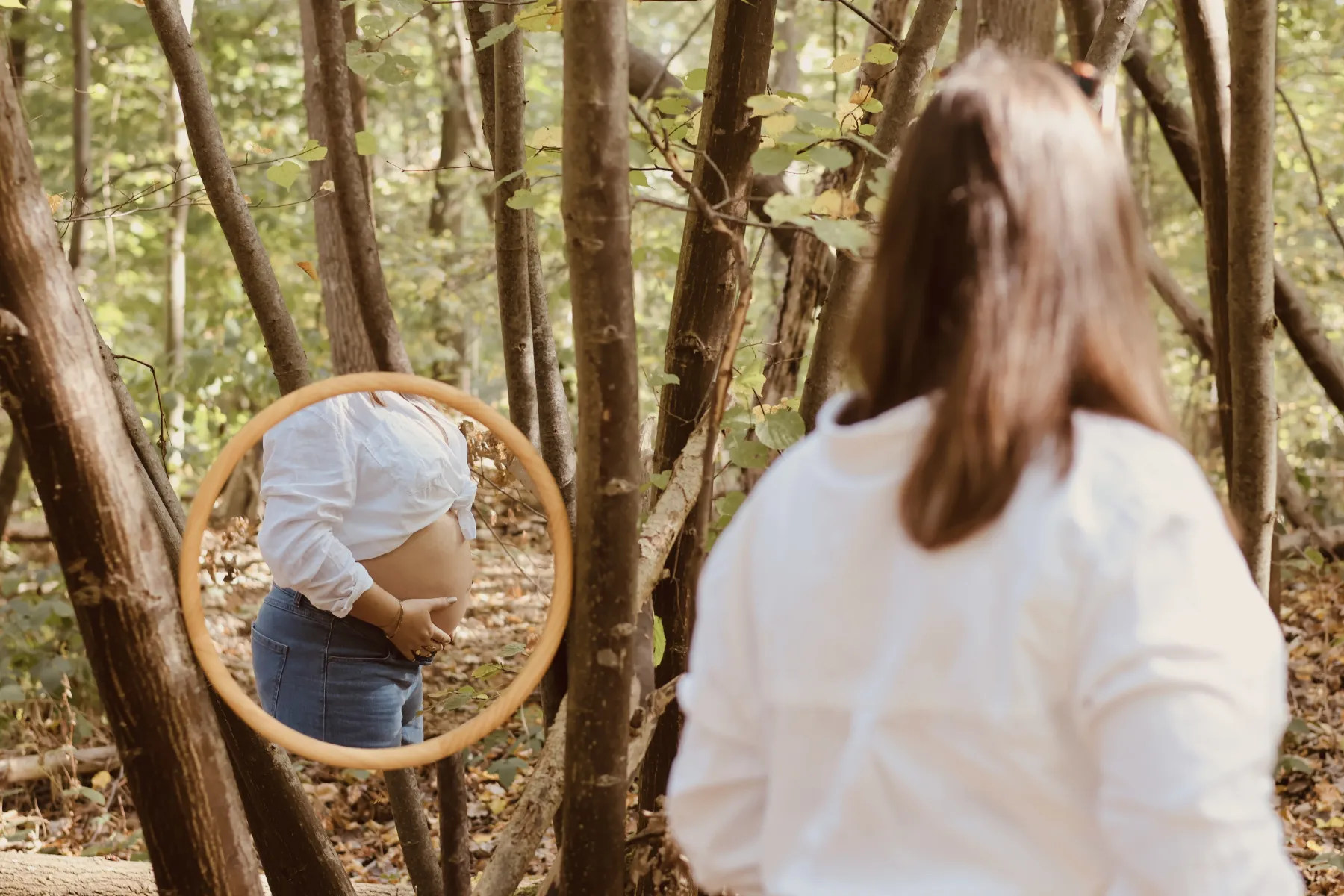 Future maman de dos, reflet de son ventre rond dans un miroir en forêt