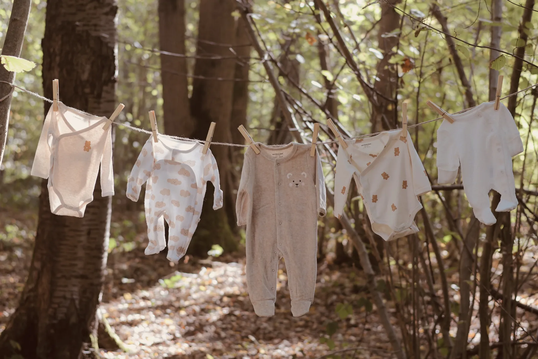 Petits vêtements de bébé suspendus à un fil entre les arbres
